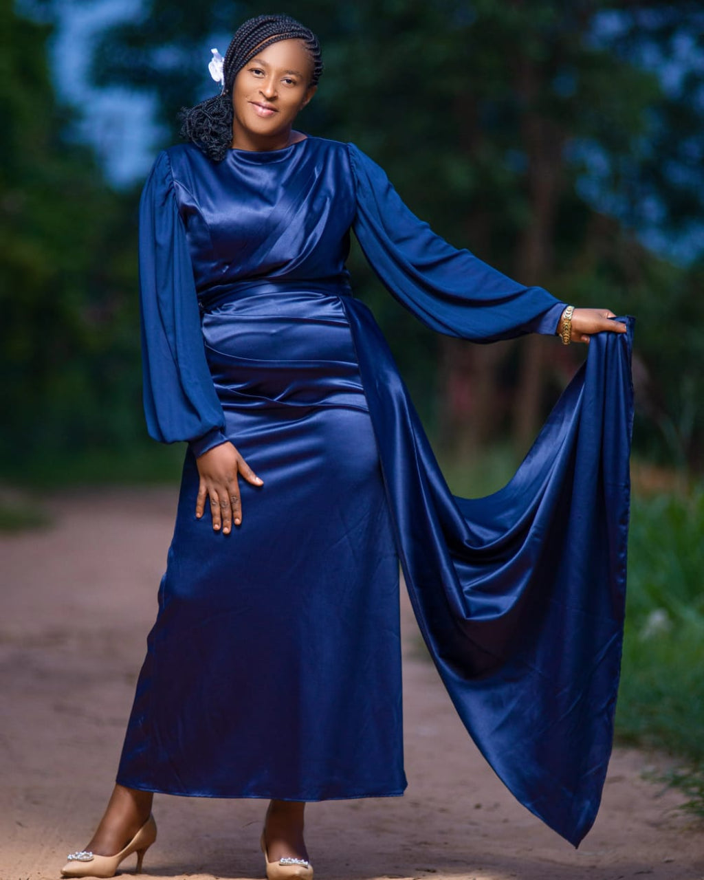 Woman in a blue dress standing outdoors with a blurred natural background